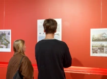 Mergina ir vaikinas prekybos centre apžiūrinėja KTU architektūros magistrų baigiamųjų darbų parodą